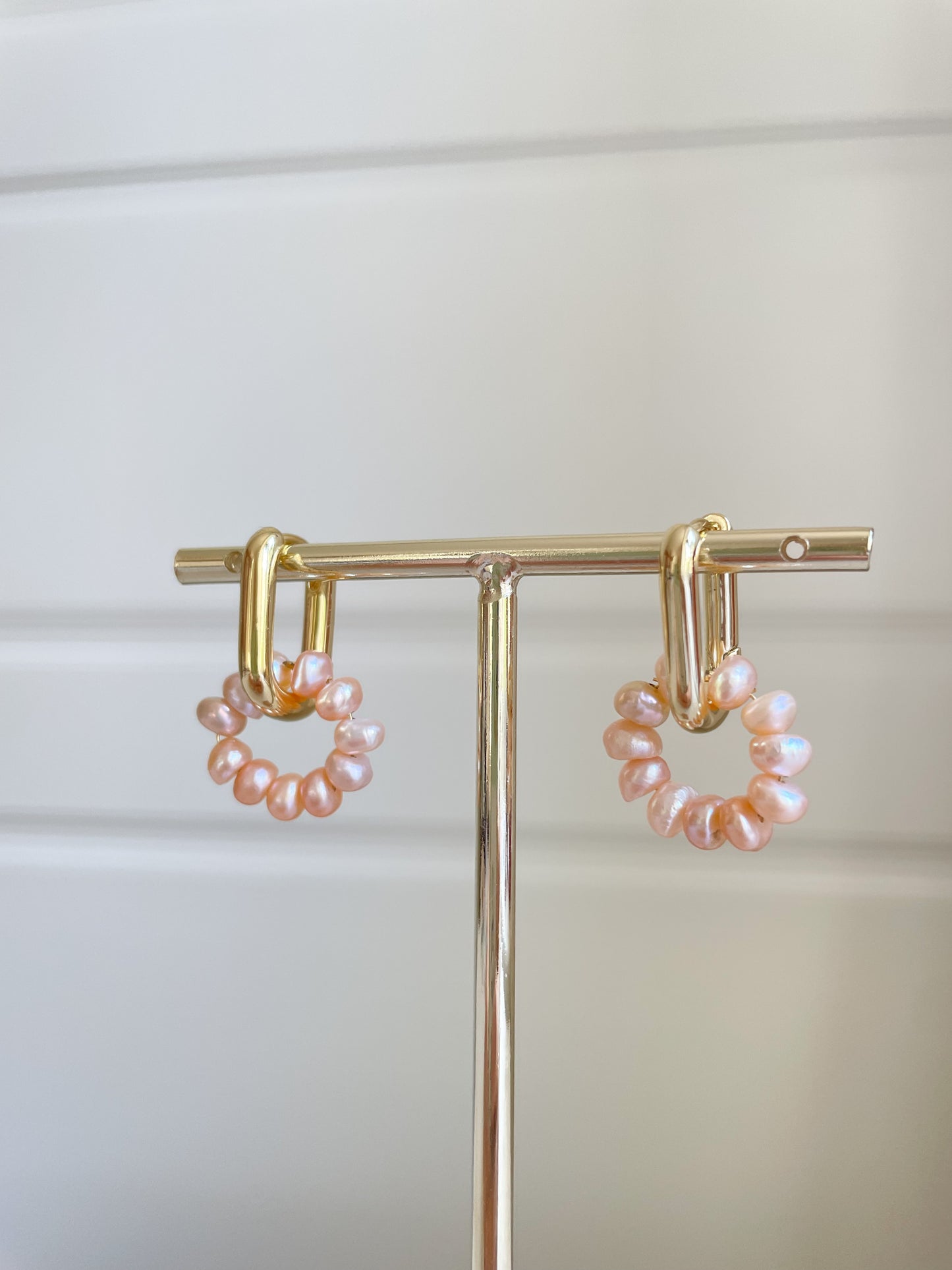 gold rectangular hoop with pink freshwater pearls threaded in a circle 